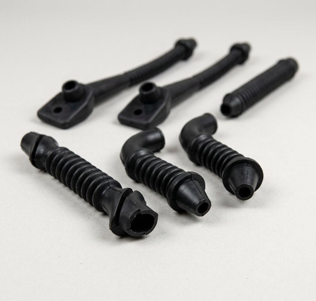 Six black wiring grommets of various shapes laid out, studio shot