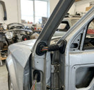 Two wiring grommets fitted to a silver car's A-pillar with cables visible