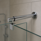 Round chrome bar running right to left from a circular wall flange to a glass panel, shower cubicle beyond.