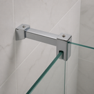 Square-section chrome bar on marble-effect white tiles, clamp closed over the edge of a clear glass panel.