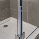 Clear T-profile seal fitted between two glass shower panels, close view near the base of the tray.