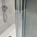 Blue-outlined zigzag seal fitted at a bifold door upright, shower head visible behind.