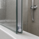 Clear tube seal with a white end cap, fitted at the base of a glass shower door.