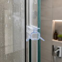 Lilac-tinted seal fitted at a shower door edge, bathroom shelf with bottles behind.