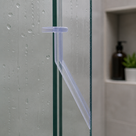 Clear T-head seal on a glass screen edge, blade angled across the gap, tiled niche behind