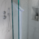 White T-seal fitted at the top edge of a glass shower panel, niche shelf behind.