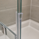 Clear loop seal fitted at a glass shower door hinge post, tiled corner behind.