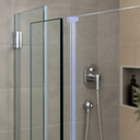Clear seal fitted at the top corner of a glass shower enclosure, chrome shower head behind.
