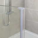 Clear seal fitted at the top corner of a glass shower enclosure, chrome shower head behind.