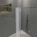 Clear H-profile seal outlined in blue, fitted at a glass shower corner near the shower head.