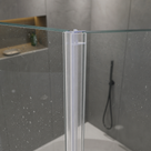 Clear seal running full height down a glass shower panel edge, grey tiles and a black shower hose behind