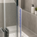 Clear frame seal fitted to a glass shower corner post, soap dispenser and plant behind