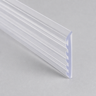 Clear ribbed packing strip on grey at a low angle, comb teeth catching the light along the edge