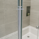 Clear bi-fold seal fitted to a wet glass shower panel edge, bathroom shelf and soap bottle behind.