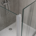 White seal fitted at a glass shower corner joint, wet glass with chrome mixer tap in view.