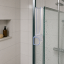 Clear dome-loop seal fitted vertically along a glass edge, niche shelf with a bottle behind.