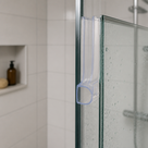 Clear dome-loop seal fitted vertically along a glass edge, niche shelf with a bottle behind.