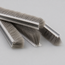Four cut lengths of brush seal with clear T carriers and short grey bristles on grey background