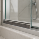 Brush seal along the lower edge of a bath screen, bristles resting on a marble ledge