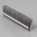Cut length of brush seal with soft grey bristles on a clear ribbed carrier, pale background