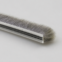End view of brush seal with clear carrier and long dense grey bristles on a pale grey background