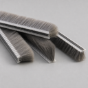 Three long brush seal strips with clear ribbed carriers and full-depth grey bristles