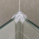 Small clear corner piece clipped to the top corner of a glass shower screen, screw hole on top face