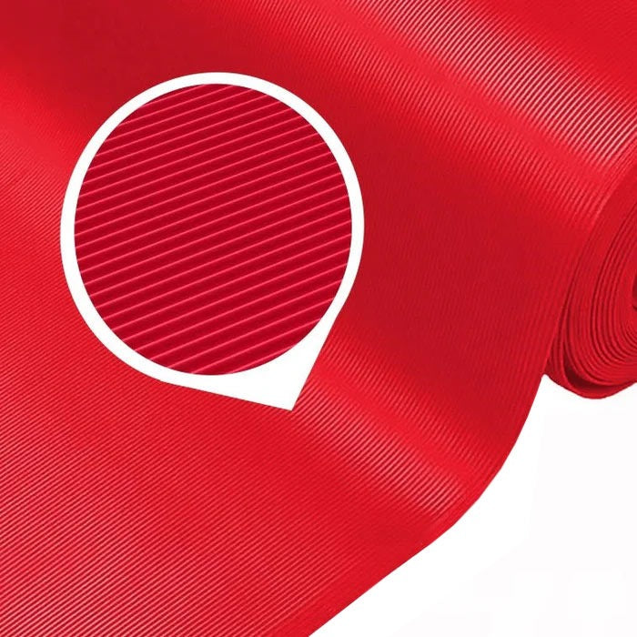 Close-up of a large roll of high-visibility red fine ribbed PVC matting, highlighting the narrow corrugated pattern of the slip-resistant surface. This mat is sold as a 1m x 25m roll and is chemical and oil resistant for industrial and commercial flooring applications.