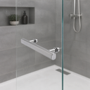 Chrome bar handle fitted to a glass shower panel, grey tiled niche with a plant and shower valve behind