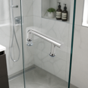 Chrome offset shower door handle on a glass door, white patterned tiles and shower hose behind