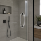 Chrome oval ring handle on a glass shower door, grey tiles with black shower controls behind