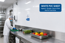 White clad wall in a food prep kitchen, worker in whites at a steel bench with trays of peppers