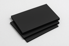 Three matt black polypropylene sheets stacked and fanned on a plain pale grey background