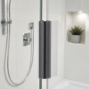 Dark grey magnet caps on clear seal fitted at shower door, plant and tiling behind