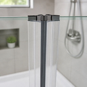 Black-capped clear seal fitted at glass shower corner, chrome head and alcove behind