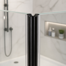 Black seal down the vertical join between glass shower panels, marble tiles and lit niche behind