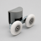Grey twin-wheel shower door roller angled on pale grey, glass clamp above two white nylon wheels