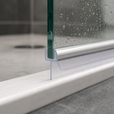Close-up of the seal on a glass edge with water droplets and a floor drain visible