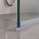 Close-up of the seal on a glass edge, floor drain and tiled surface visible behind