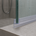 Clear J-hook seal fitted to a glass edge on a tiled bath surround, shower hose behind