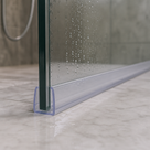 Clear seal with a flat side fin at the foot of a wet glass shower panel on marble-effect floor tiles