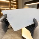 White opal acrylic sheet held by gloved hands in a retail interior