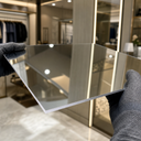 Gloved hands holding a silver acrylic mirror panel reflecting a lit retail interior