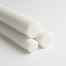 Three white acetal rods stacked on a white studio background with their round cut ends facing the camera