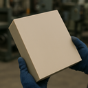 Navy-gloved hands holding a thick beige square polypropylene sheet in a blurred workshop