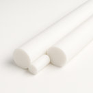 Three white PTFE rods in differing diameters lying diagonally on a plain white studio background, cut ends forward