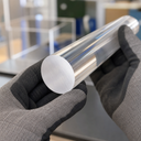 Clear acrylic rod end held by gloved hands, showing the circular cut face