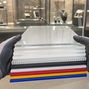 Stack of A4 acrylic sheets in mixed colours and finishes held by gloved hands