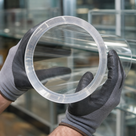 Clear acrylic tube ring end filling the frame in grey and black gloves, glass shelving beyond