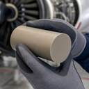 Short tan PEEK rod held in a grey glove, jet engine intake blurred in the background